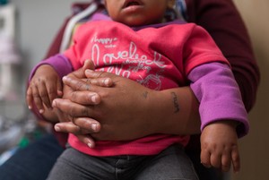 Tattoos are seen on a female ex-convict hand as she holds her baby