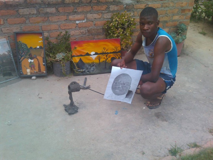 Photo of boy next to paintings