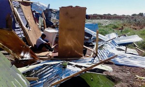 Photo of a young man sitting in a demolished shack