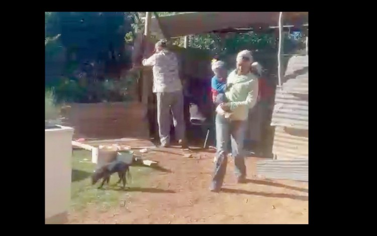 Photo of a man pulling down a shack structure