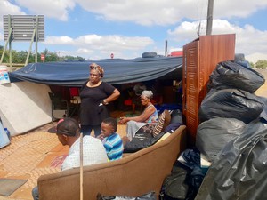 Photo of a family and their possessions under plastic