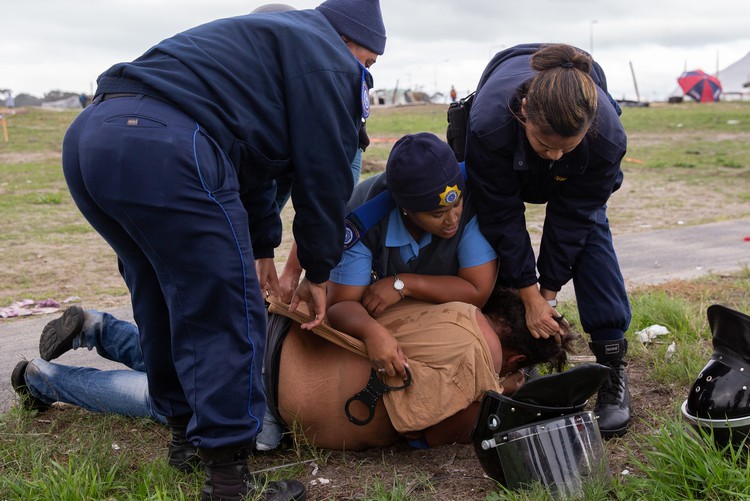 Photo of a woman being detained after protests turn violent in Parkwood.