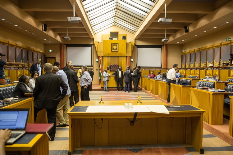 Photo of parliamentary committee room with people standing around