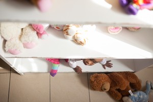 Photo of baby peering out from a shelf