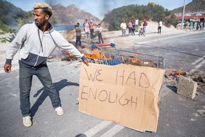 Photo of burning barricade with man holding placard