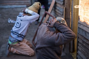 Photo of two men kneeling with their hands behind their heads