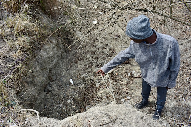 Photo of a man pointing to a dry river bed