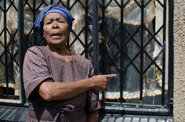 Photo of woman in front of house with broken windows