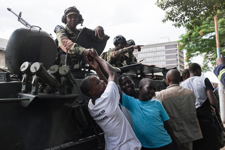 Photo of soldier in a tank and citizens smiling