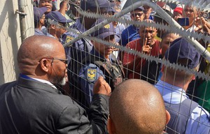 Photo of a crowd behind a wire fence