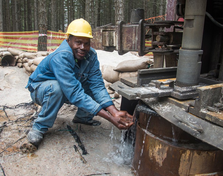 Photo of man drinking water from borehole