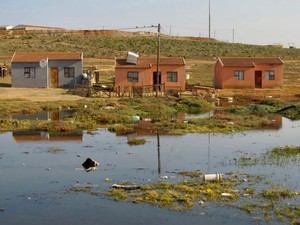 Photo of three houses next to a river