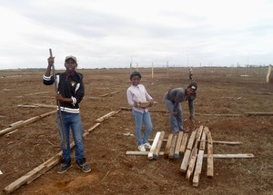 Photo of three people rebuilding a shack