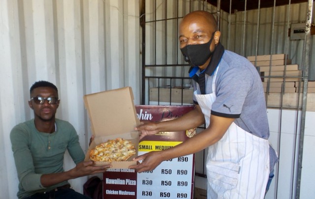 Photo of two people with a pizza