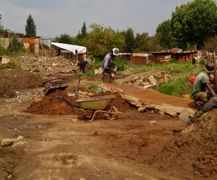 Photo of men digging with a wheelbarrow