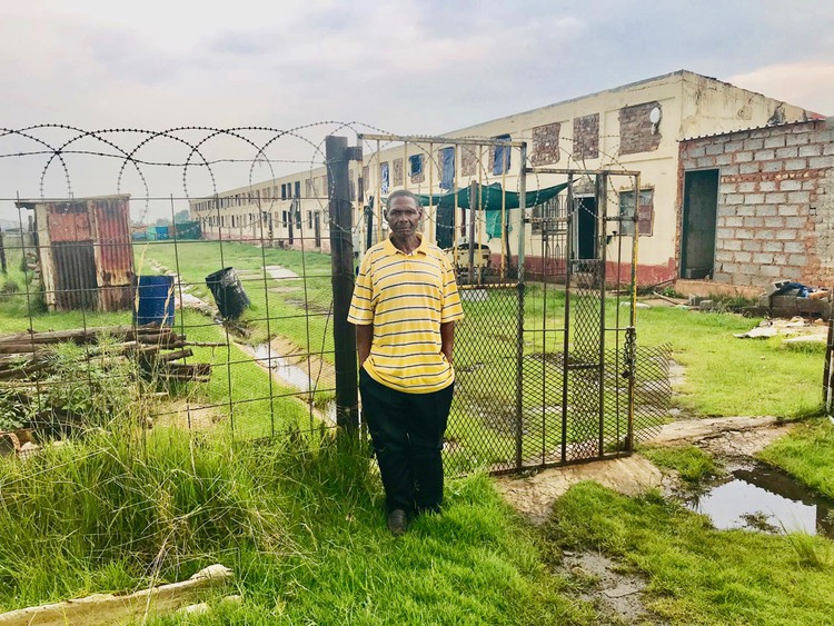 Photo of a man standing in front of an old mining compound