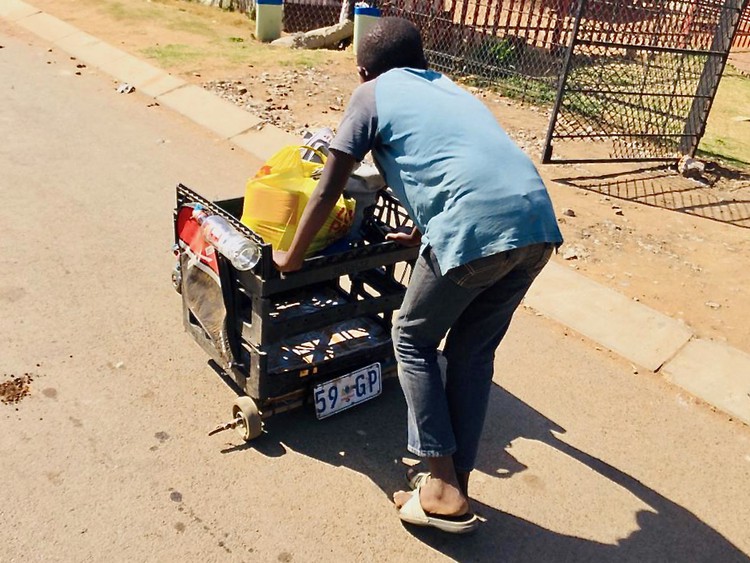 Photo of a boy pushing a makeshift trolley