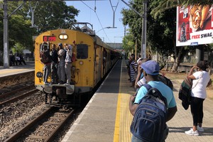 Commuters hang on to trains.