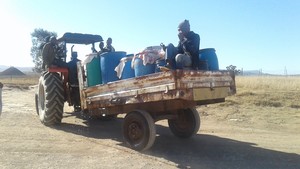 Photo of tractor and trailer with wster barrels.