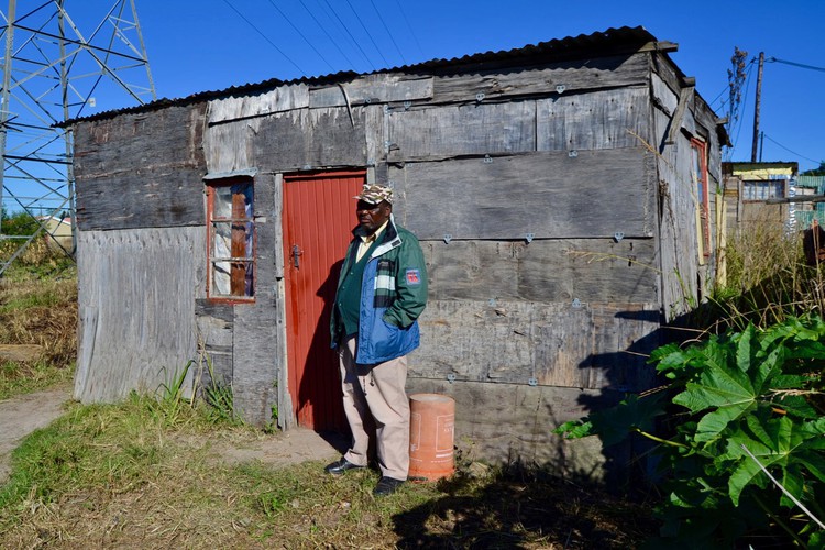 Photo of a man in front of his shack