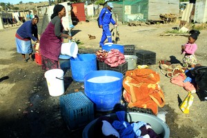 Picture of people waiting in line to draw water from a tap