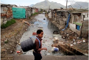 Photo of boy walking past canal in Masiphumelele.