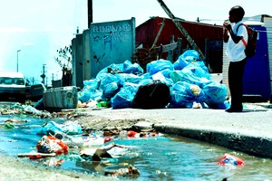 Photo of a boy at the roadside with piles of rubbish