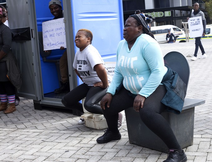 Photo of two women pretending to use toilets