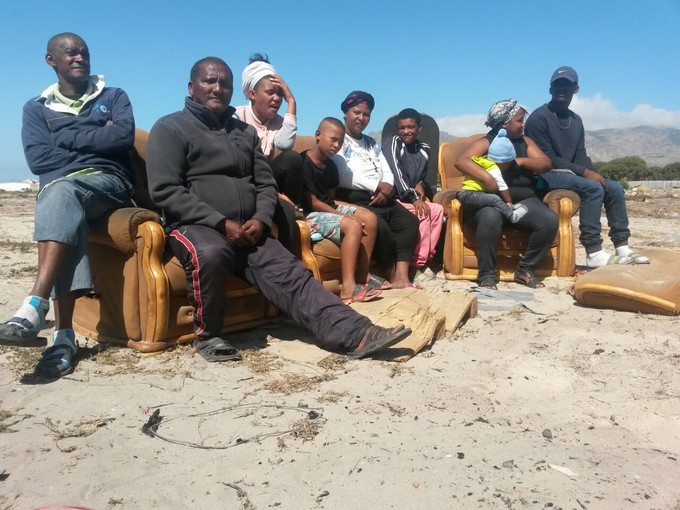 Photo of people sitting on a couch in an open sandy field