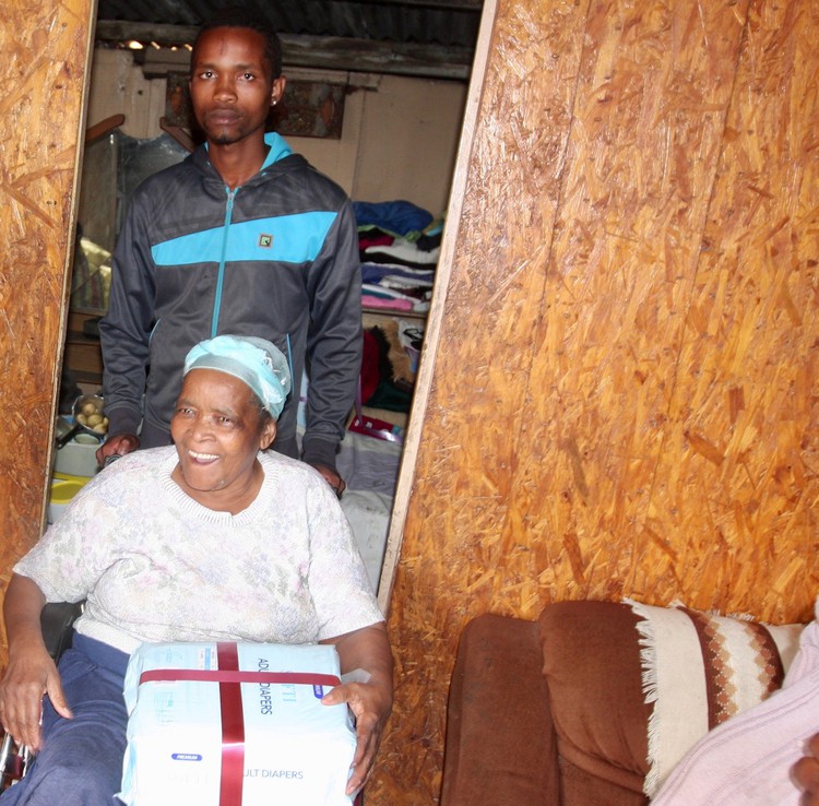 Photo of a woman in her wheelchair with her grandson standing behind her