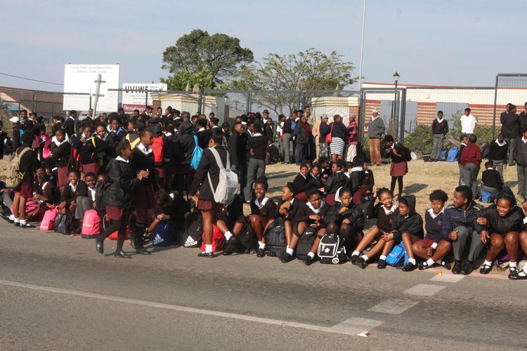 photo of leaners sitting outside the school