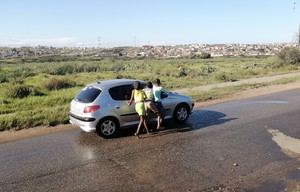 Photo of a car and three children standing at the driver's window