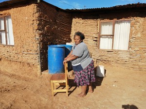 Photo of woman in front of mud house