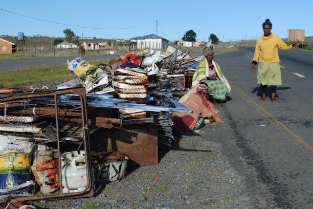 Photo of a woman standing beside the roadside with recyclables