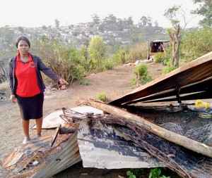 Photo of a woman next to a demolished shack