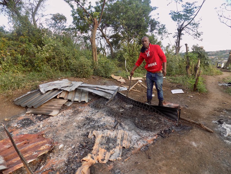 Photo of a man and a burnt our shack