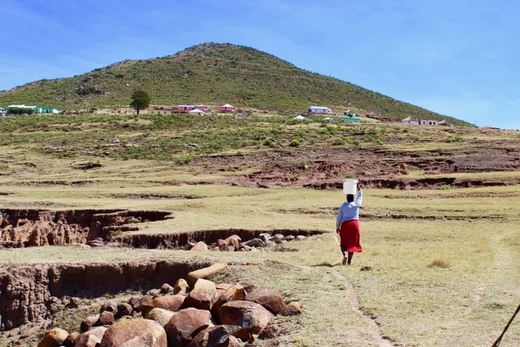 Photo of a woman walking with a bucket on her head