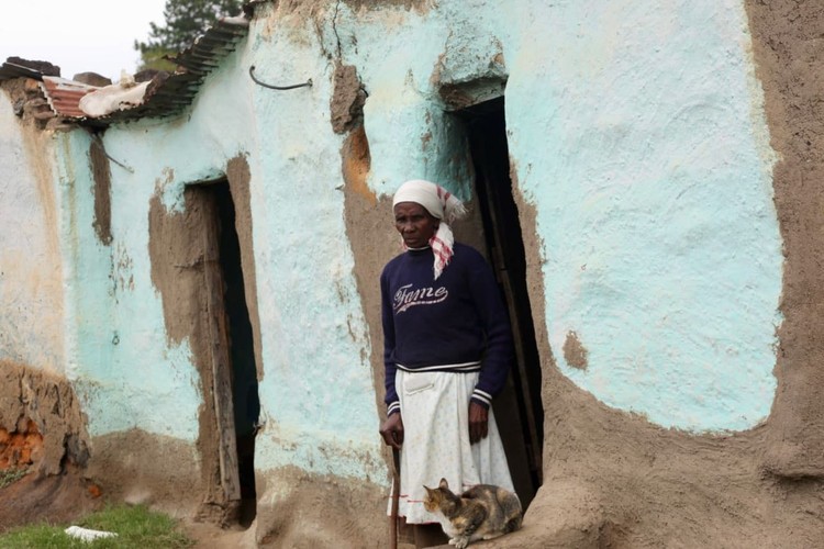 Photo of a woman and a dilapidated house