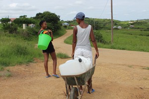 Photo of women pushing a wheelbarrow with containers to fetch water