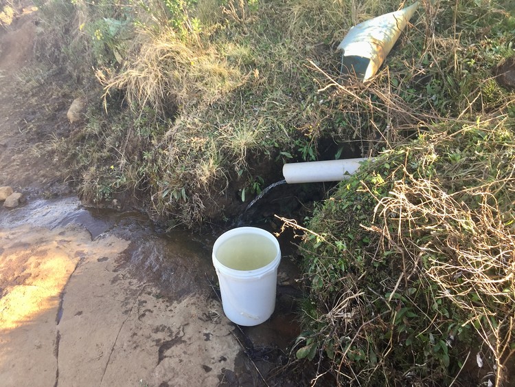 Photo of a pipe with water and a bucket