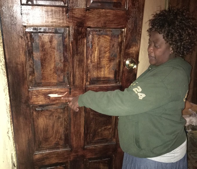 Photo of woman pointing to apparent bullet hole