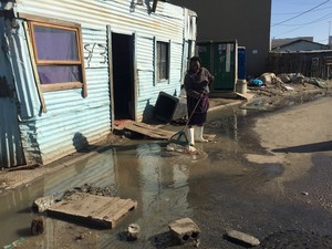 Photo of woman sweeping sewage water.