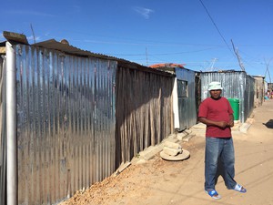 Photo of man in front of shack