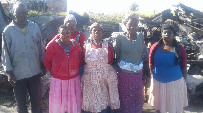 Photo of people against background of burnt rubble