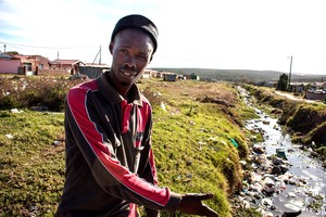 Photo of man pointing to polluted stream