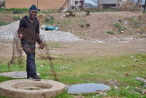 Photo of a man next to an open manhole