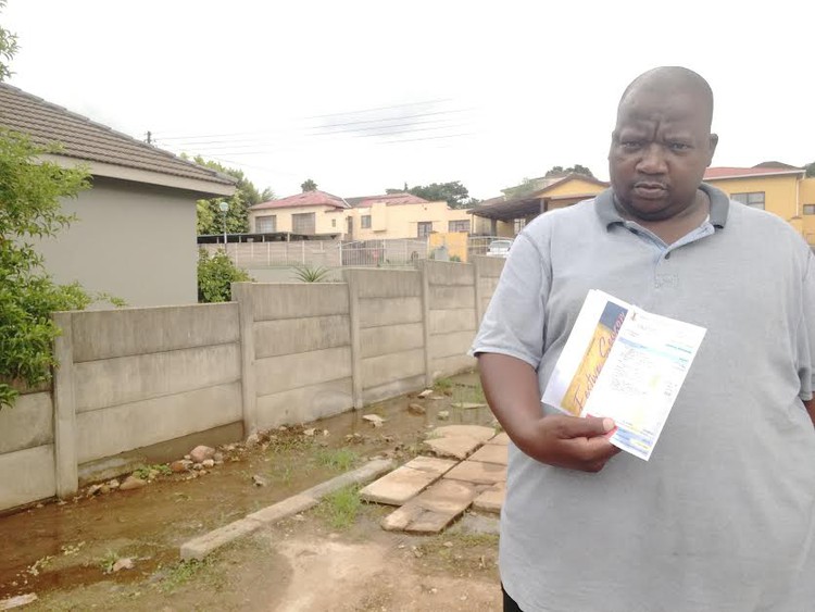 Photo of man with water leak behind him