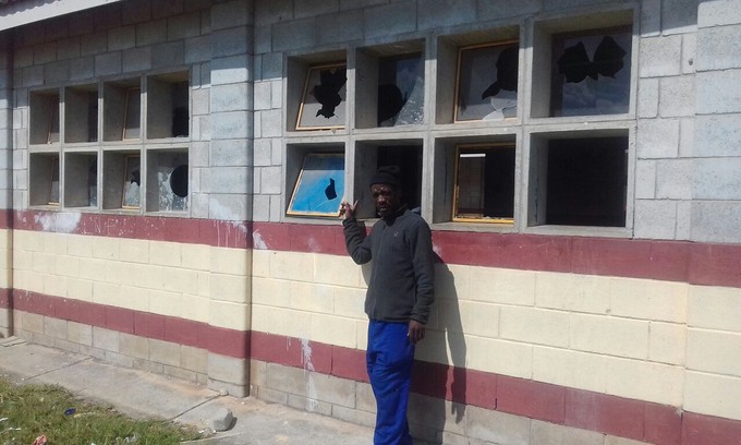 Photo of man pointing at vandalised classrooms