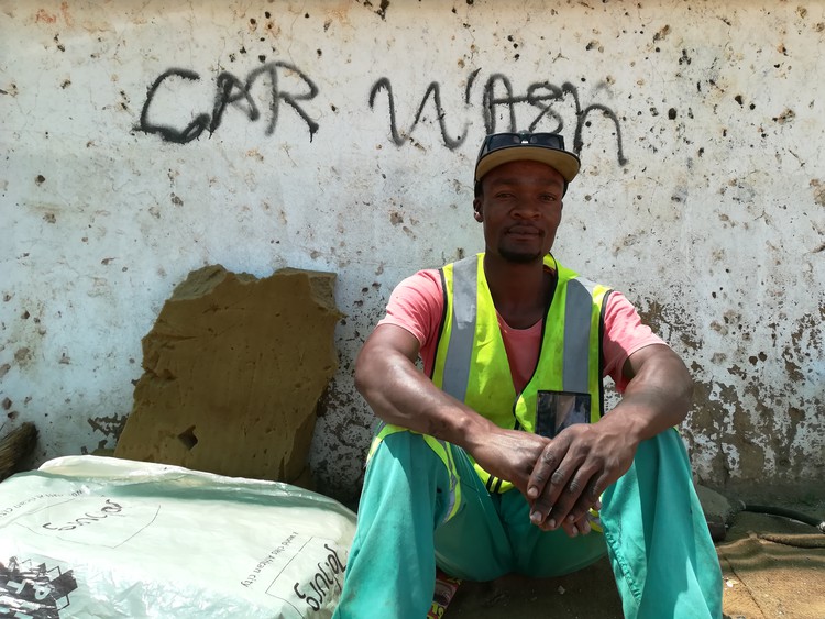 Photo of man sitting on sidewalk