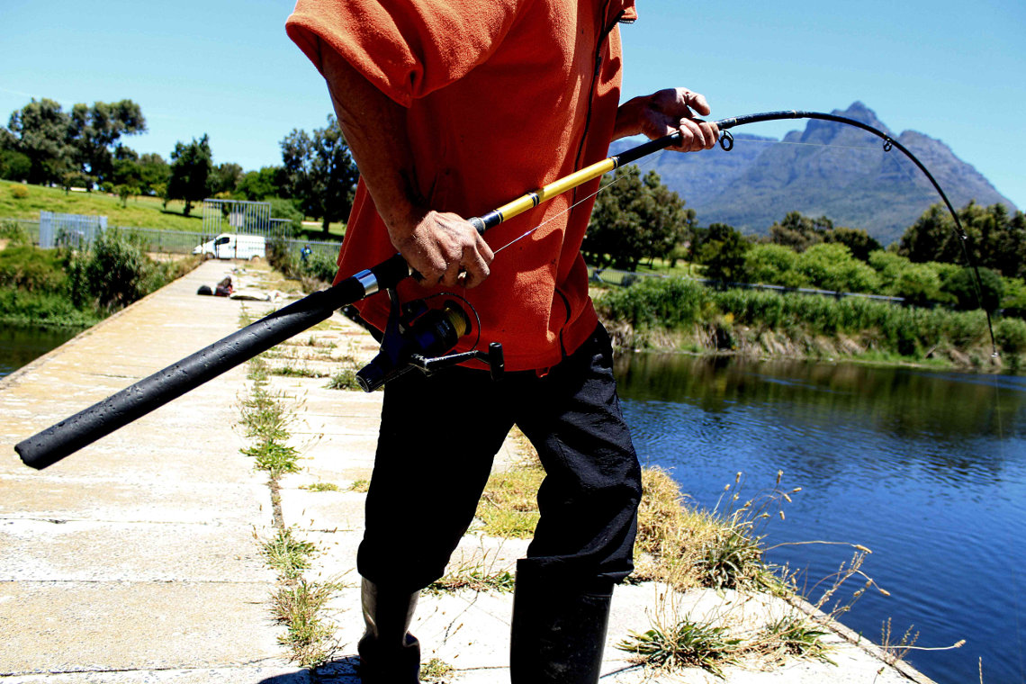 In order to reach the fish he has caught, Wayne pulls it to the side of the river.